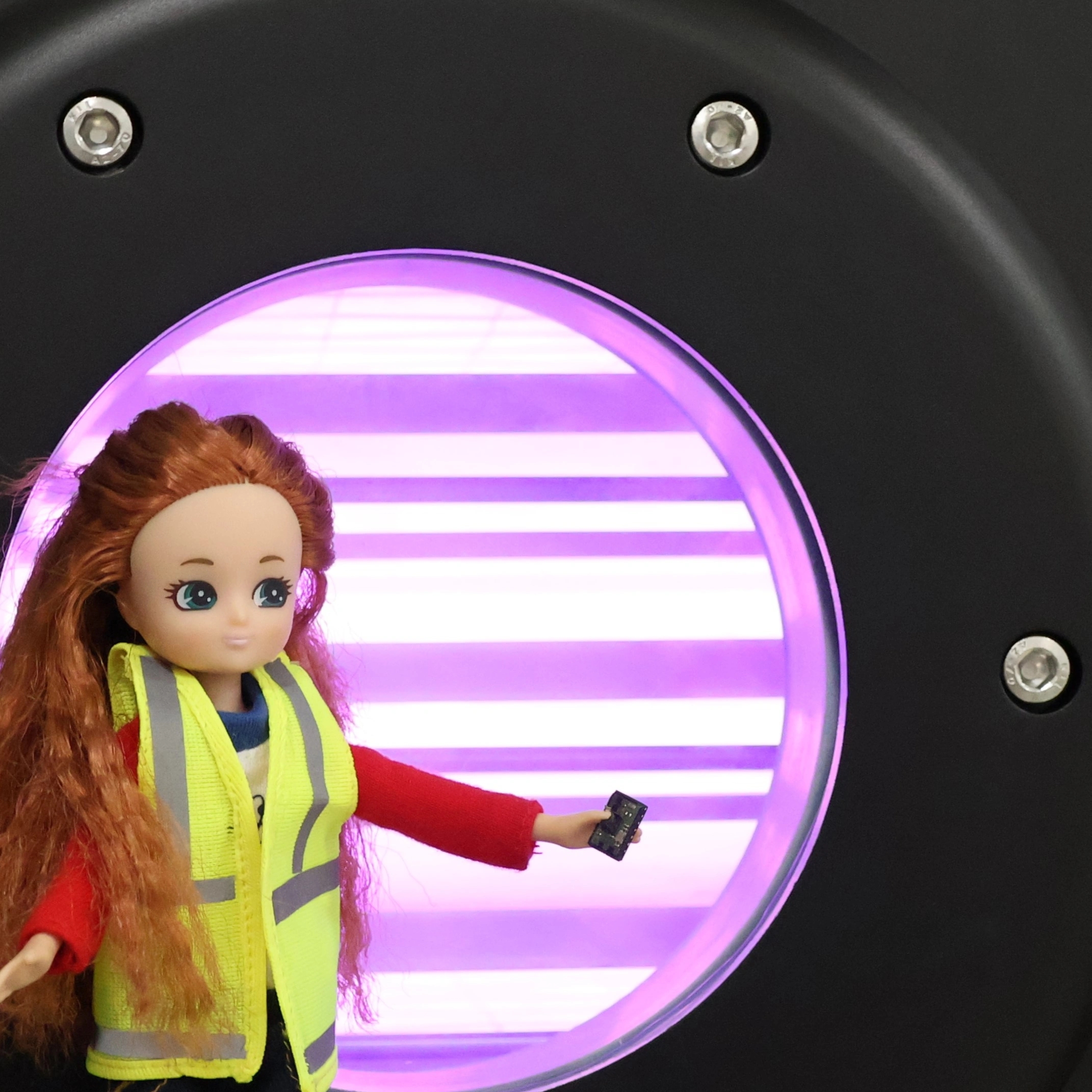 A lottie-doll stands in front of a purple spot light