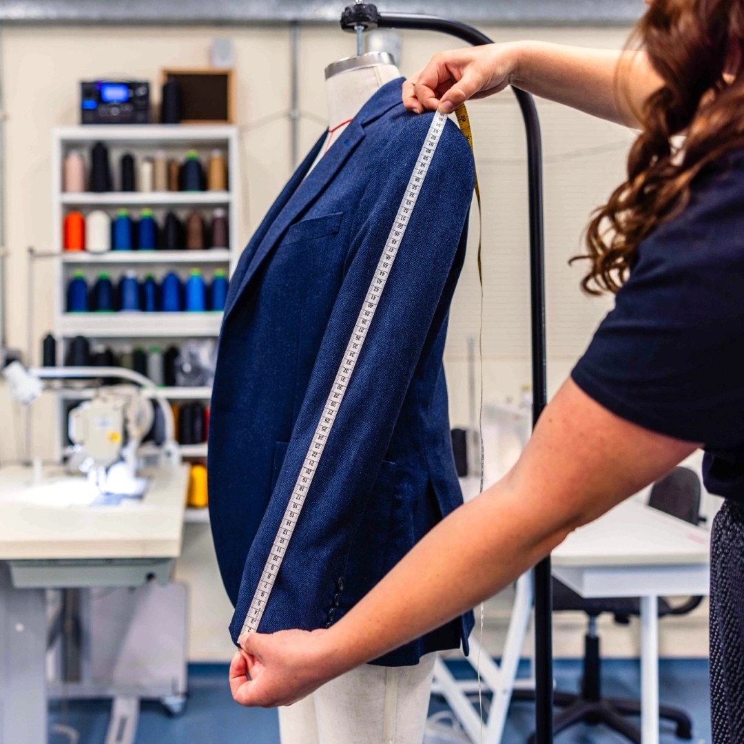 Jacket on a mannequin with a woman measuring the sleeve length