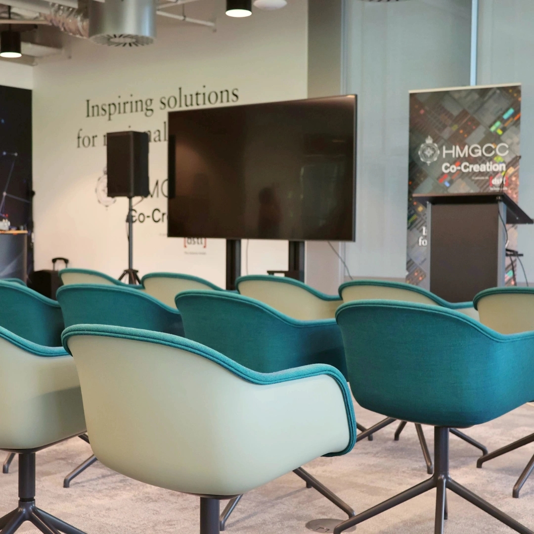 Empty chairs set out for speeches in front of a TV screen and speakers